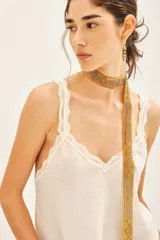 Top negro de viscosa con breteles finos y escote en V con puntilla. Presenta apliques de tachas termo adhesivas en el frente.