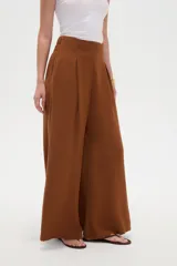 Pantalón ancho de poliéster color marrón, de tiro alto con pinzas en la cintura y punto smock en la parte posterior.