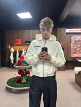 Hoodie de color blanco con capucha, diseño de corte holgado y estampado gráfico en la espalda con tipografía negra.