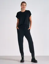 Enterito negro de modal y poliéster, con mangas cortas, escote redondo, laterales abiertos, cintura elastizada y bolsillos laterales. El pantalón es estilo jogger con terminación ajustada en el ruedo.