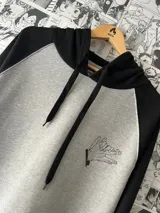 Canguro gris con capucha y mangas largas negras. Estampado en el frente con diseño de manos en blanco y negro.