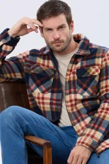Campera polar de hombre con estampa a cuadros en tonos neutros y azules, confeccionada con tejido polar suave. Presenta cierre frontal, cuello camisero, bolsillos con solapa en el pecho y calce cómodo.
