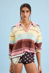 Buzo de algodón tejido, de calce relajado y silueta amplia con diseño de rayas horizontales en tonos pastel de amarillo, celeste, rosa y marrón. Tiene cuello tipo polo con terminación artesanal en crochet y mangas amplias.