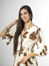 Vestido largo color crudo con estampado floral marrón, escote en V cruzado, mangas tres cuartos con volados y falda con niveles fruncidos.