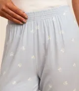Pantalón de pijama celeste con estampado de patitas blancas, cintura elástica y puños ajustados.