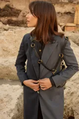 Tapado largo de sastrería con diseño bicolor y asimétrico. Una mitad presenta un tejido negro con rayas diplomáticas, mientras que la otra mitad es de un tejido a cuadros en tonos tierra. Cuenta con botones de nácar, bolsillos con tapa y abertura trasera.