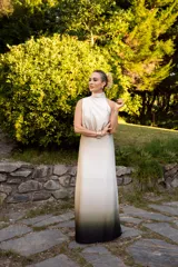 Vestido largo de satén con diseño degradé que transiciona de marfil en la parte superior a verde oscuro y negro en el dobladillo. Presenta cuello halter, diseño superior irregular, cintura elástica y falda larga con aberturas laterales.
