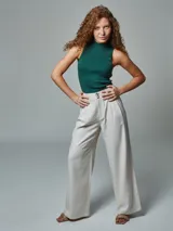 Pantalón de vestir color crudo, de corte recto, con bolsillos laterales y traseros. Se ajusta a la cintura con cinturón de cuero marrón.