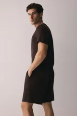 Conjunto de pijama de dos piezas color marrón oscuro, compuesto por una remera de manga corta con cuello redondo y un short con cintura elástica ajustable mediante cordón y bolsillos laterales.