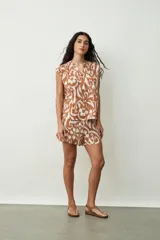 Blusa negra sin mangas, con cuello mao y abertura frontal con botones. Presenta frunces en la zona de los hombros, dándole un calce holgado.