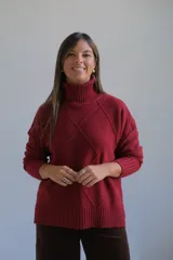 Polerón de cuello alto con diseño de rombos en relieve, mangas largas con puños acanalados y ruedo asimétrico con aberturas laterales.