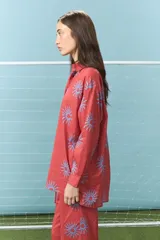 Camisa de algodón color rojo con estampado de soles en color azul, de corte oversize, cuello camisero y mangas largas.