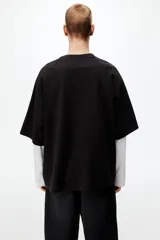 Remera negra de algodón pesado con corte oversized, cuello redondo acanalado, mangas raglán cortas con franja blanca decorativa con el logo de Lotto y logo impreso en el pecho.