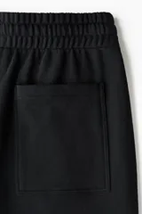 Pantalón de jogging de felpa de algodón pesado, con corte de pierna ancha y silueta relajada. Presenta cintura elástica con cordón ajustable, bolsillos laterales al bies y un bolsillo de parche en la parte trasera.