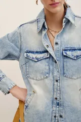 Camisa de denim color celeste con lavado claro, de manga larga, con bolsillos frontales con solapa y cierre de botones metálicos.