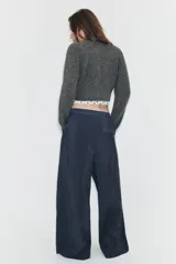 Pantalón de tiro alto con diseño cruzado tipo pareo en el frente, pernera ancha y caída fluida.