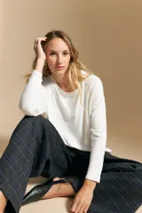 Remera de manga larga con silueta relajada y caída fluida, confeccionada en tejido suave con cuello redondo y aberturas laterales en el ruedo.