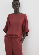 Blusa de diseño recto y color bordó, con cuello redondo, mangas tres cuartos y cierre de botón en la parte posterior del cuello.