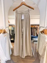 Pantalón palazzo de calce amplio y caída fluida, confeccionado en mezcla de liocel y lino, con cintura elástica fruncida, lazo de ajuste frontal y bolsillos laterales.