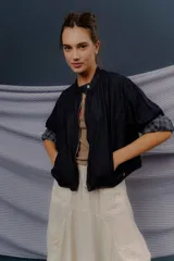 Campera de denim azul oscuro, de corte corto y estilo bomber, con cierre frontal y detalles de forrería a cuadros visibles en el interior de los puños.