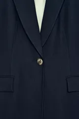 Blazer de cuello solapa y manga larga con cierre frontal de un botón. Presenta bolsillos delanteros con solapa y diseño estructurado.