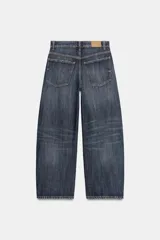 Jeans de tiro medio con diseño baggy barrel, cinco bolsillos y costuras laterales torcidas. Presenta cierre frontal con cremallera y botón metálico.