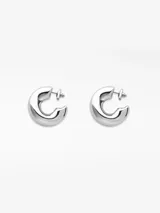 Par de aros gruesos plateados con forma irregular y cierre tipo broche.