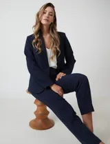 Blazer sastrero entallado color beige, con cuello de solapa, cierre frontal con un botón a tono y hombreras estructuradas. Presenta bolsillos laterales con solapa y forro interno.