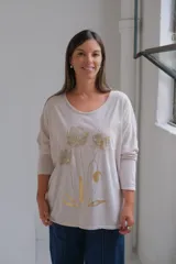 Remera de corte holgado y mangas largas, color beige, con estampado floral en tonos dorados en la parte frontal.