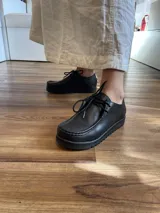 Zapato acordonado de cuero negro con suela de goma.