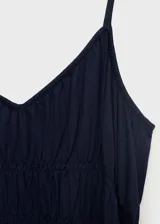 Vestido corto negro de tirantes finos, con escote en pico y diseño fruncido en la parte superior del cuerpo. Presenta un corte recto y fluido con un ligero vuelo en el ruedo.