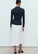 Cardigan de punto fino acanalado, color negro, con cuello en V con solapa y cierre frontal de botones.