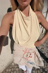 Top negro sin mangas con cuello halter drapeado y cierre posterior con botón.
