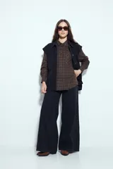 Camisa tipo leñadora de corte oversize, con estampado de cuadros en tonos negro y marrón. Presenta cuello clásico, cierre frontal con botones y mangas largas con puños abotonados.