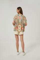 Blusa de lino con diseño estampado multicolor en tonos tostado, turquesa y rosado, corte holgado, mangas cortas y escote en V.