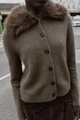 Chaqueta de punto color marrón con cuello de solapa desmontable en pelo sintético. Presenta cierre frontal con botones, manga larga y terminaciones en rib.