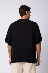 Remera de punto color crema, de manga corta, con cuello redondo acanalado y corte oversize.