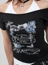 Remera negra con diseño ajustado de manga corta y escote off-shoulder, que incluye un detalle superpuesto simulando una bikini blanca por debajo. Posee estampado gráfico al frente con motivos florales y texto.