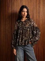 Blusa de gasa con estampado abstracto en tonos oscuros, corte holgado con frunces, cuello redondo con lazo de ajuste y mangas largas amplias con puños.