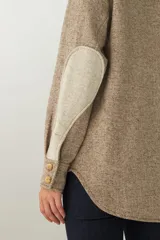 Camisa estilo leñador color beige con textura en espiga, de manga larga, con cuello clásico, cierre frontal con botones, dos bolsillos de parche con solapa abotonada en el pecho y puños abotonados. Confeccionada en lana fina sin teñir.