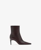 Botin de cuero caprino color marrón oscuro, con diseño de punta fina y tacón kitten de 6,5 cm. Cuenta con cierre de cremallera lateral.