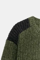 Jersey de punto de cuello redondo y manga larga, con diseño de textura acanalada en color verde oliva y detalles de paneles en color gris oscuro en los hombros.