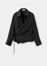 Camisa de tejido satinado color negro, de corte recto con diseño cruzado que se ajusta mediante un lazo lateral. Presenta cuello camisero, escote en V y mangas largas con puños anchos abotonados.
