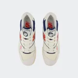 Championes urbanos New Balance modelo 550, color blanco con detalles en azul y rojo, confeccionados en cuero y malla, con logo "N" característico en los laterales.