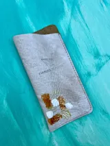 Portalentes de cuero color blanco con diseño pintado a mano en tonos cobre, dorado y blanco, de la línea Ottenta de Carolina De Cunto con logo grabado.