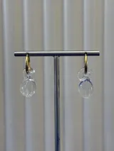 Aros de argolla dorada con dije colgante de vidrio de Murano transparente con vetas azules y textura estriada.