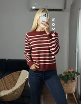 Sweater de punto con diseño de rayas horizontales negras sobre fondo blanco, cuello redondo y puños y ruedo acanalados.