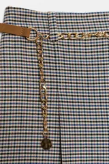 Bermuda larga de tiro alto con diseño de estampado a cuadros tipo pata de gallo. Presenta pinzas delanteras, corte amplio y un cinturón integrado que combina una tira de cuero sintético con una cadena metálica dorada. Cierre lateral con cremallera oculta.