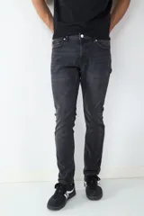 Jean de corte slim fit en color negro lavado, con diseño clásico de cinco bolsillos, cierre frontal con botón y cremallera.