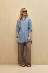 Vestido camisero de silueta amplia color azul, con cuello camisero, botonadura frontal completa y mangas largas.